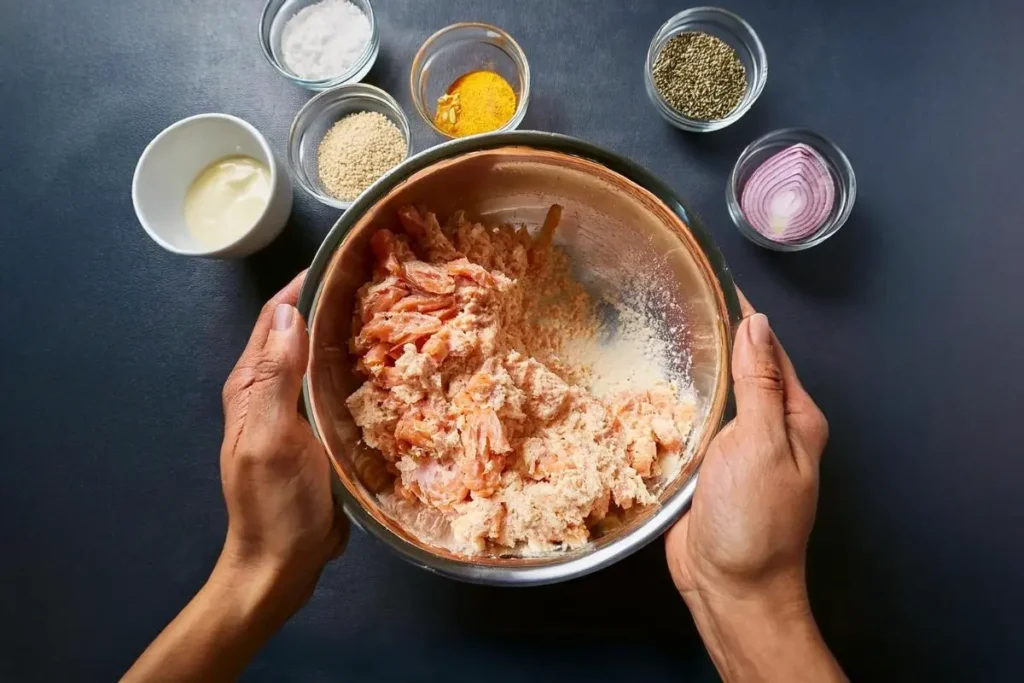 Mixing ingredients for salmon patties recipe with mayonnaise in a bowl.