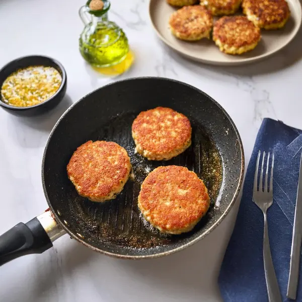 Golden salmon patties frying in a skillet.