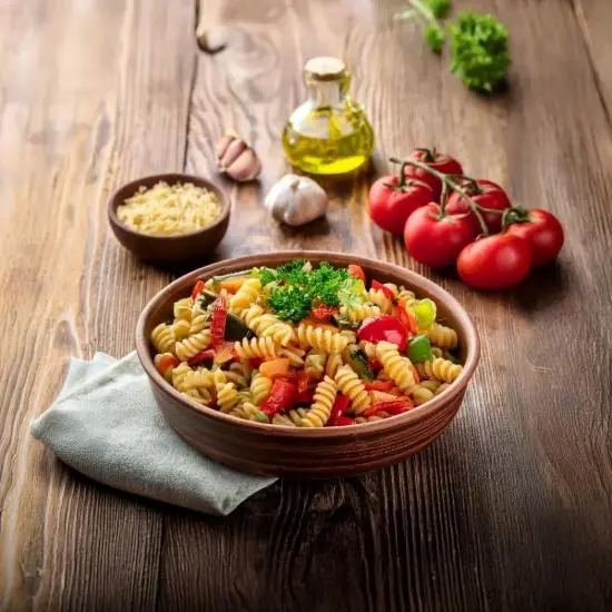 Casarecce pasta mixed with roasted vegetables like bell peppers and zucchini.