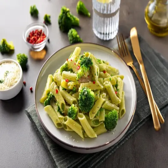 Broccoli pasta served on a white plate with garlic and red pepper flakes.