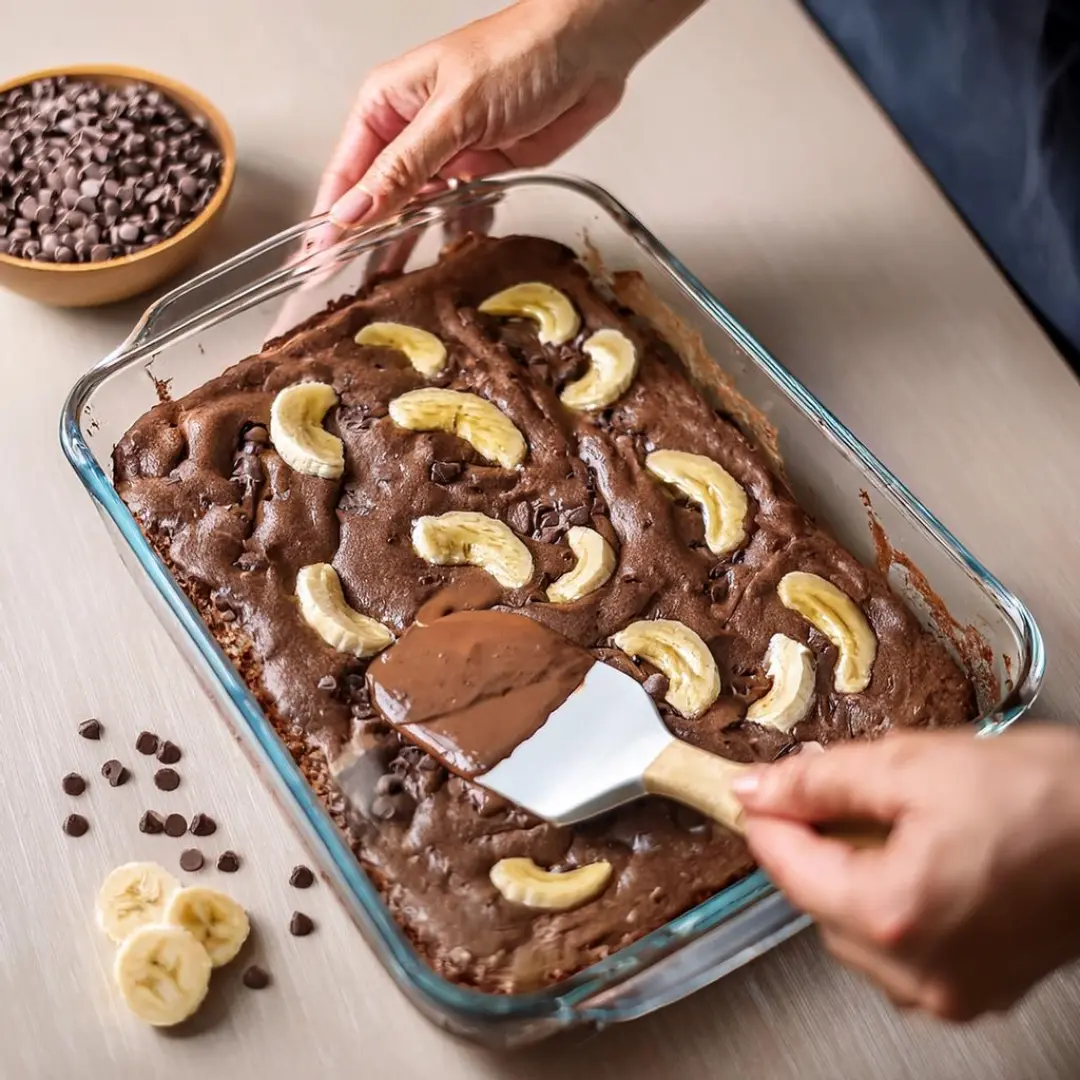 Spreading banana brownie batter in a glass baking dish.