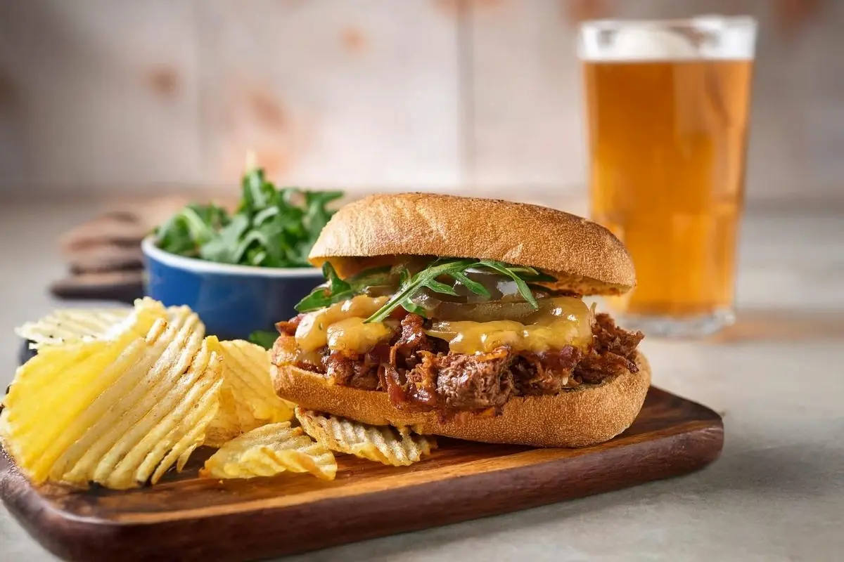 Gourmet leftover meatloaf sandwich with toppings and chips.