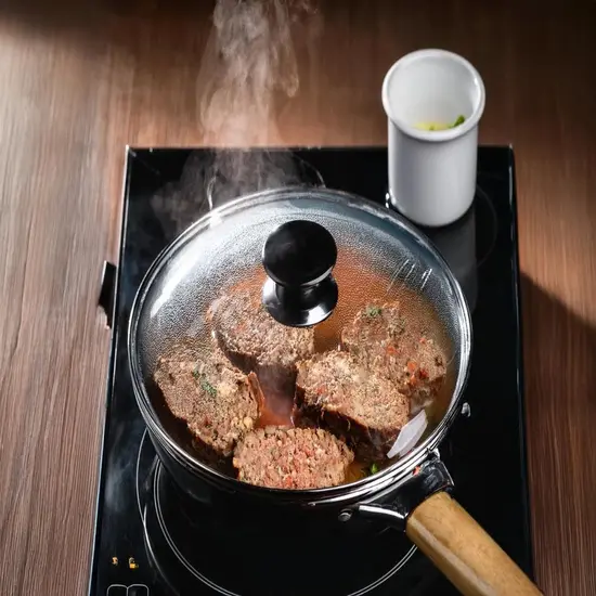 Meatloaf slices reheating in a covered skillet on a stovetop.