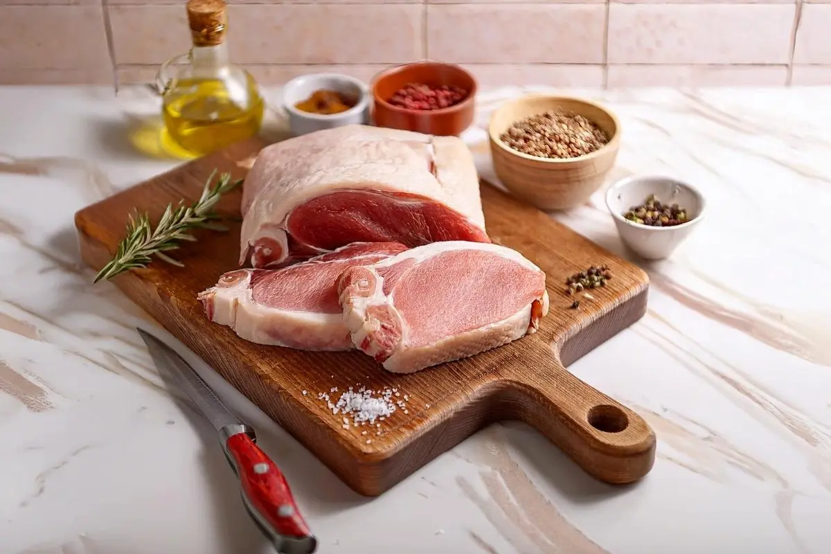 Fresh lamb shoulder and lamb fat on a wooden butcher's board for Adana Kebab preparation.