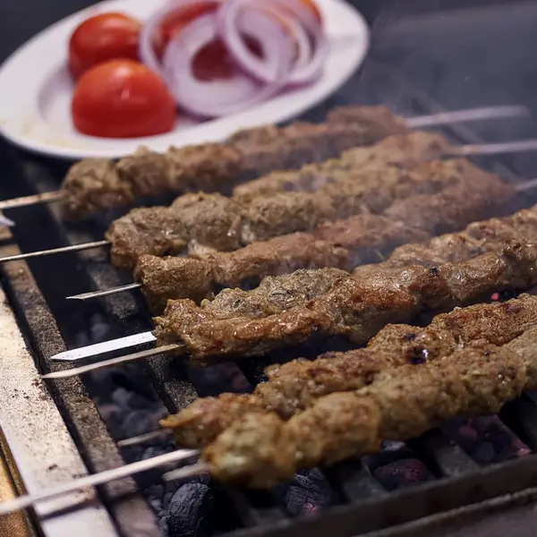 Adana Kebabs grilling over charcoal, with juices from the minced lamb and onion keeping them tender.