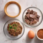 A top-down view of ingredients for hash brownies, including cannabutter, cocoa powder, sugar, eggs, vanilla extract, and chocolate chips.