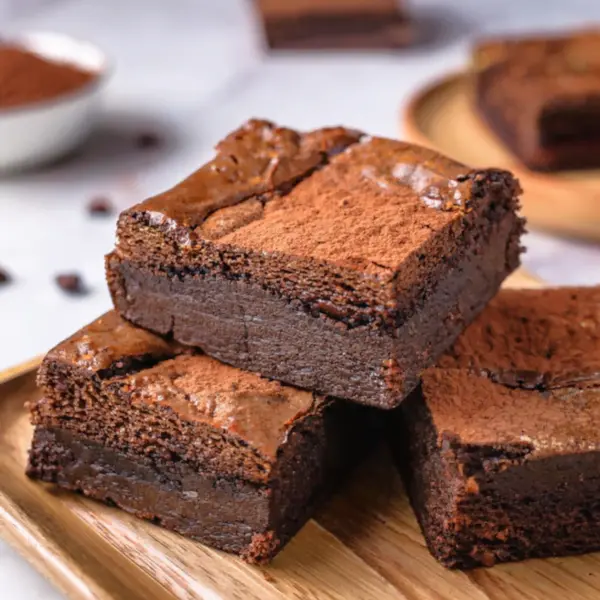 A stack of freshly baked hash brownies with a crisp top and fudgy center, served on a wooden tray.